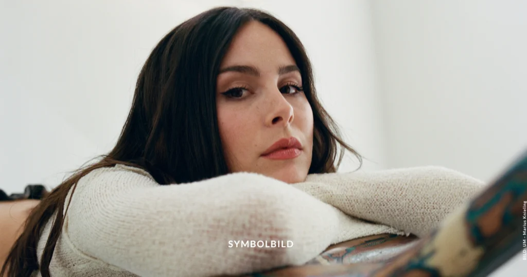 Das Bild zeigt Lena Meyer-Landrut, die mit dem Gesicht zur Kamera steht und ihren Kopf auf den Armen ablegt, die sich auf dem Handlauf einer Treppe befinden. Symbolbild