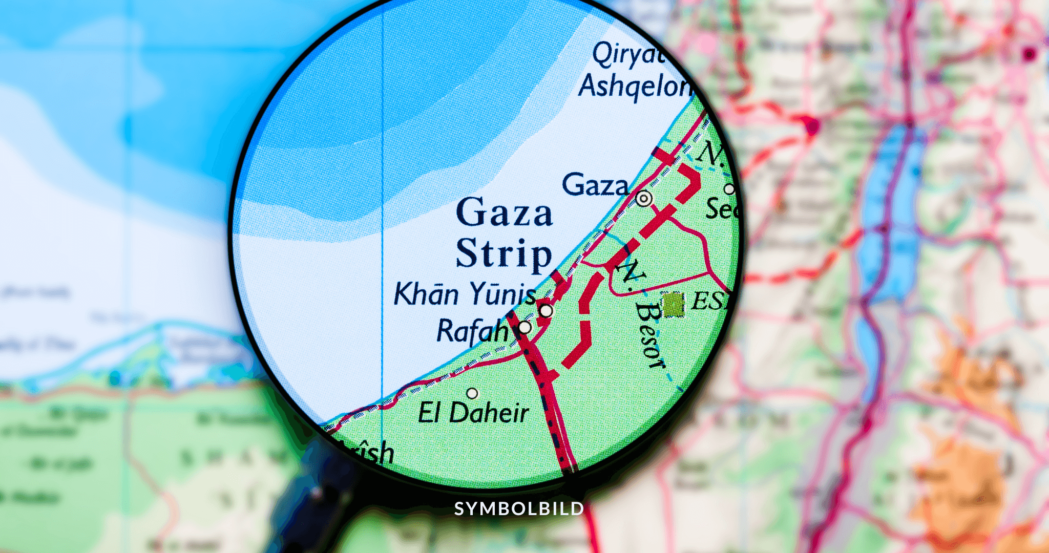 Das Bild zeigt eine Nahaufnahme einer Karte durch eine Lupe. Der Fokus liegt auf dem Gazastreifen, auch Orte wie Khan Yunis und Rafah sind sichtbar. Die Karte enthält Details wie Straßen, Grenzen und Textbeschriftungen. Gaza Waffenstillstand Symbolbild