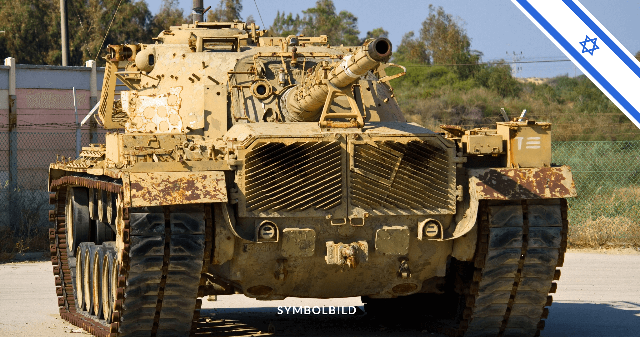 Das Bild zeigt einen israelischen Militärpanzer mit einer Kanone. Der Panzer ist in einem Tarnmuster bemalt, hauptsächlich in Brauntönen und Beige. Im Hintergrund sind Bäume und ein klarer blauer Himmel zu sehen. In der oberen rechten Ecke des Bildes befindet sich eine israelische Flagge. Am unteren Rand des Bildes steht der Text “SYMBOLBILD”. Israel Waffenstillstand