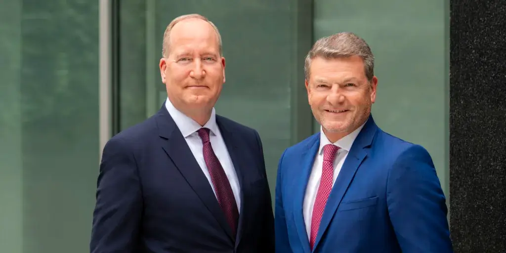 Das Bild zeigt den BDL-Präsidenten Jens Bischof und den Hauptgeschäftsführer Dr. Joachim Lang (von links nach rechts), die nebeneinander stehen und Business-Anzüge tragen. 
Der Hintergrund besteht aus einer reflektierenden Glasfassade.

© BDL | Die Hoffotografen