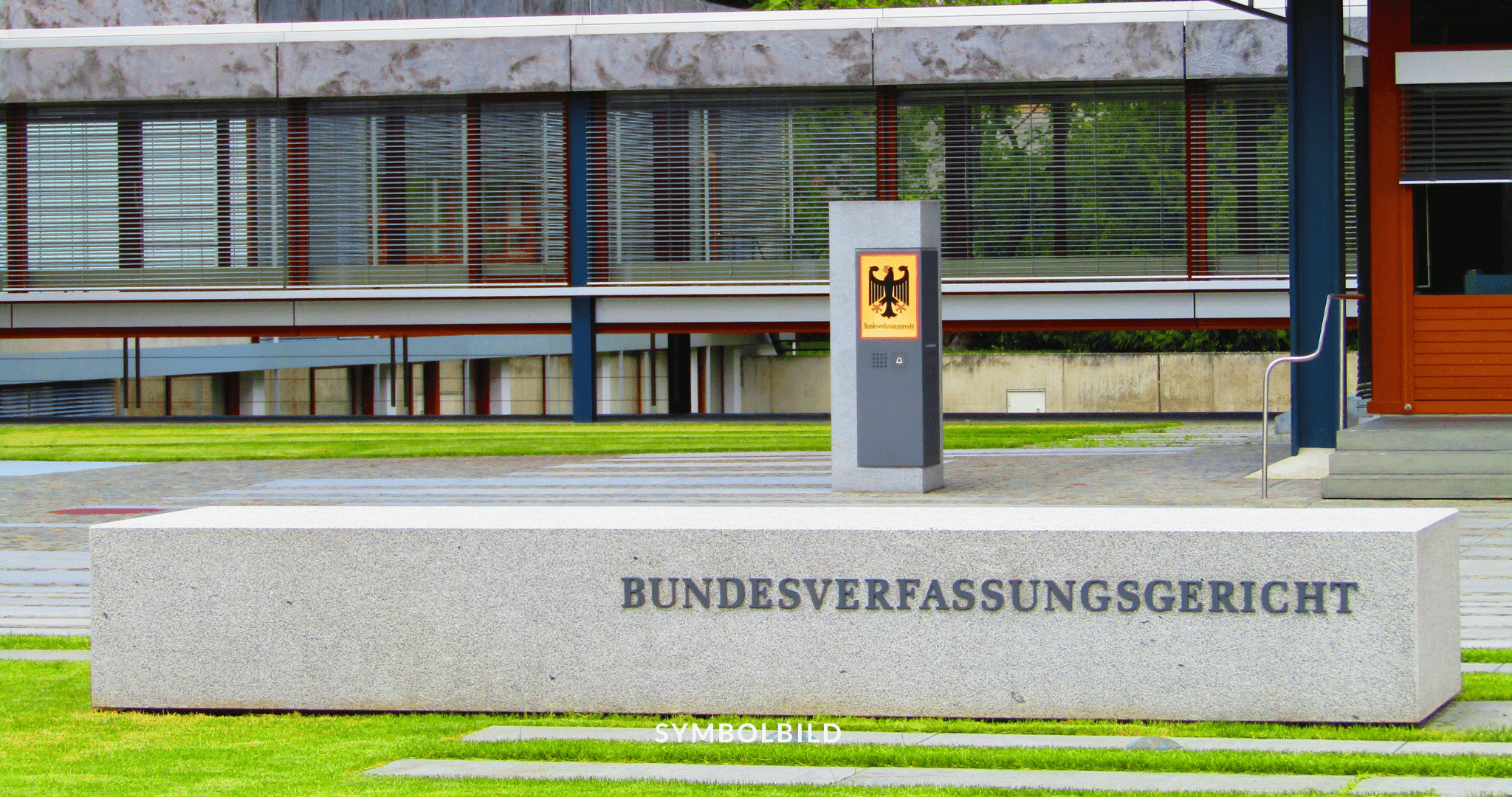 Das Bild zeigt das Gebäude des Bundesverfassungsgerichts in Deutschland. Vor dem modernen Gebäude mit großen Fensterfronten und einem Eingang befindet sich ein gepflegter Rasen. Auf einem Betonblock vor dem Gebäude steht der Schriftzug “BUNDESVERFASSUNGSGERICHT”. SYMBOLBILD Bundesverfassungsgericht Urteil zum hessischen Verfassungsschutzgesetz