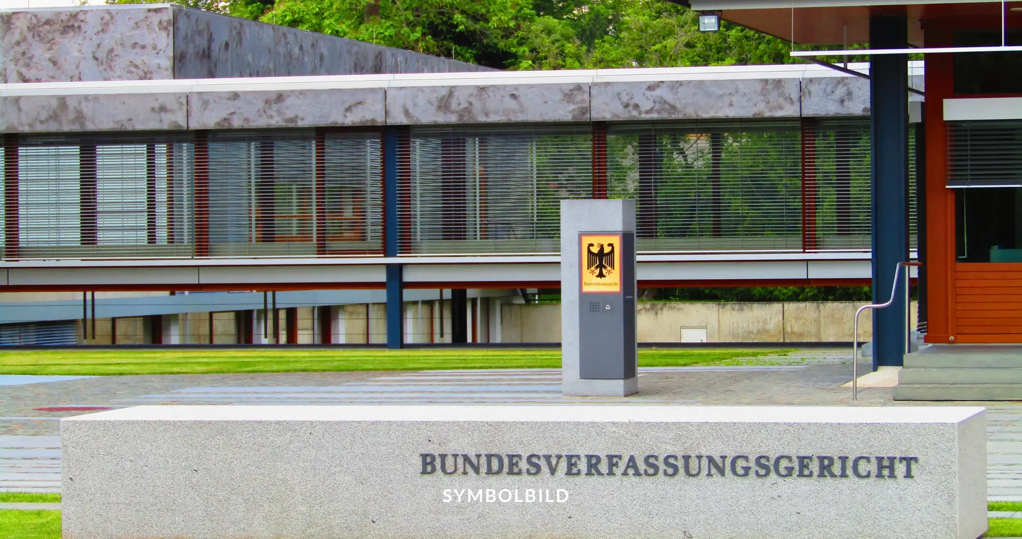 Das Bild zeigt die Außenansicht des Bundesverfassungsgerichts, eines modernen Gebäudes mit großen Fenstern und einem Flachdach. Vor dem Gebäude steht ein Schild mit der Aufschrift “BUNDESVERFASSUNGSGERICHT”. SYMBOLBILD Bundesverfassungsgericht erklärt BKA-Gesetz in Teilen für verfassungswidrig