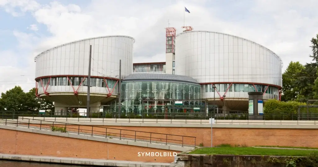 Das Bild zeigt das Gebäude des Europäischen Gerichtshofs für Menschenrechte (EGMR) in Straßburg, Frankreich. Es ist architektonisch markant, mit zwei großen, runden, silberfarbenen Türmen und einer gläsernen zentralen Struktur. Die runden Gebäude wirken fast futuristisch und heben sich durch ihre Größe und Form von ihrer Umgebung ab. Zwischen den Türmen befindet sich ein moderner, gläserner Eingang, der das Zentrum des Gebäudekomplexes darstellt. Über dem Gebäude weht eine Europaflagge. Symbolbild EGMR: Europäischer Gerichtshof für Menschenrechte verurteilt Deutschland